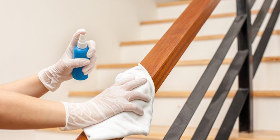 hands withe gloves disinfecting stairs