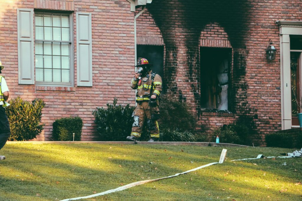 firefighter walking out of burned house