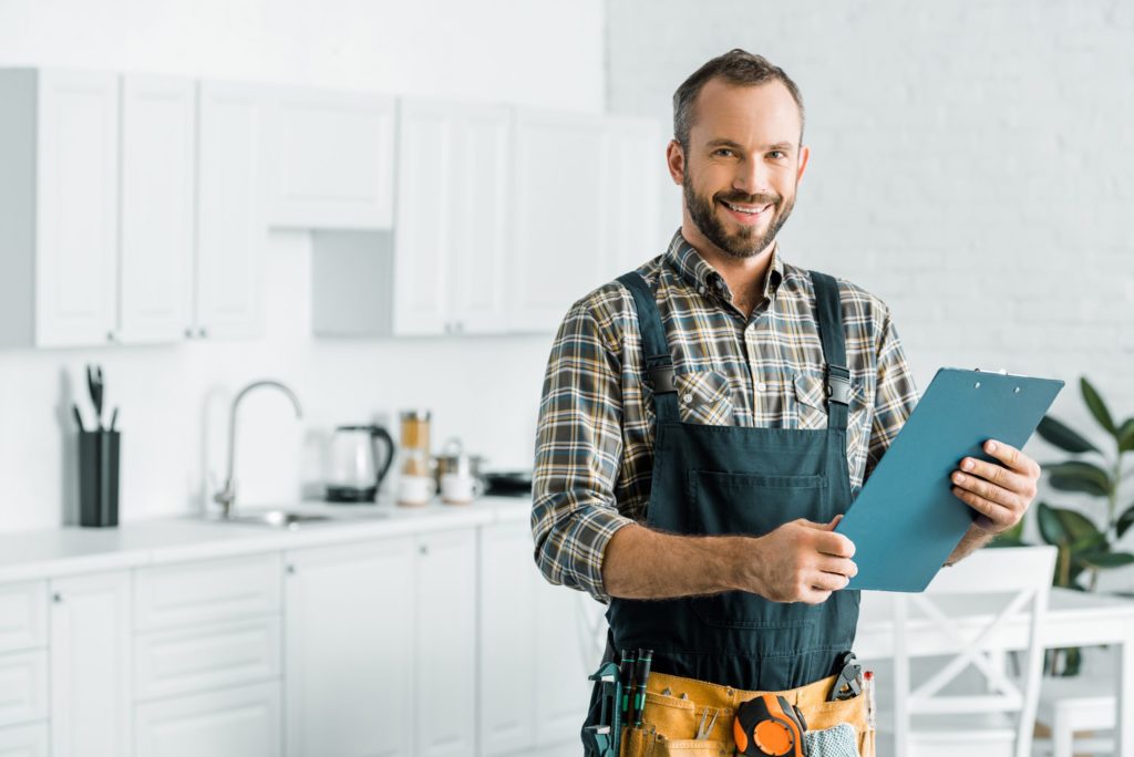 damage contractor smiling holding papers in a kitchen