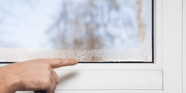 Man's hand pointing to the window glass humidity. Room airing problem.